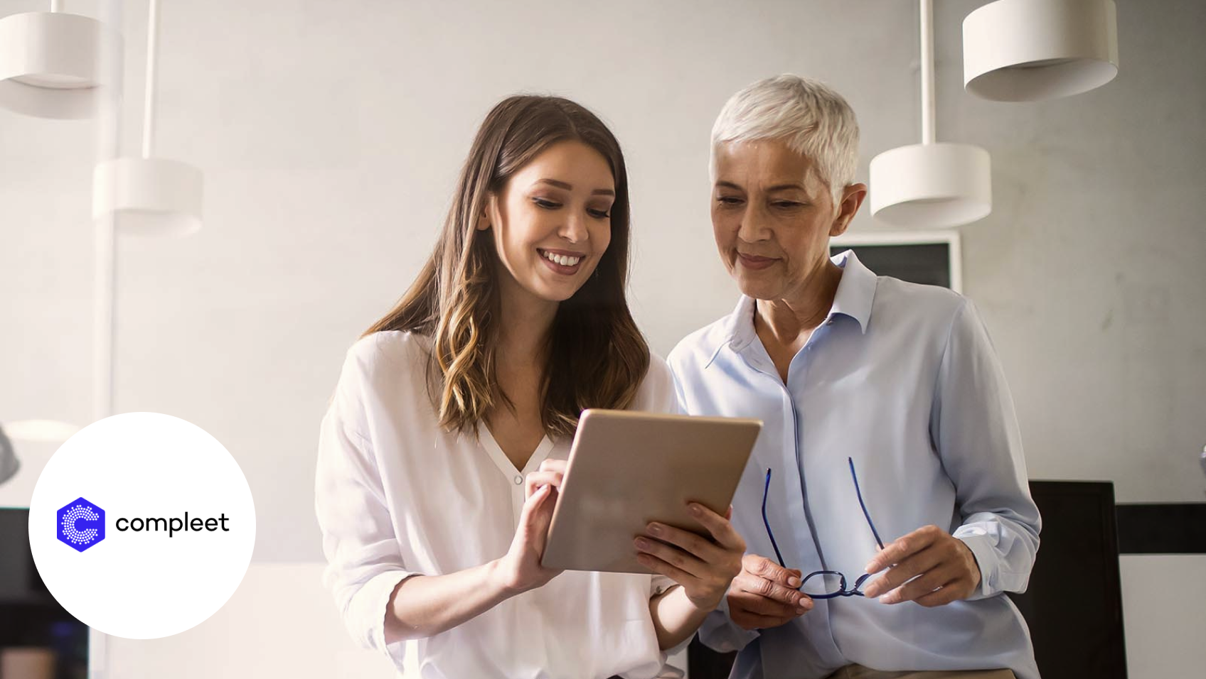 Zwei Frauen unterhalten sich im Büro und schauen auf ein Tablet