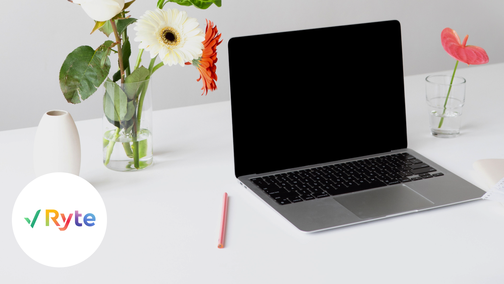 Ein Laptop steht auf einem weißen Tisch in Umgebung von bunten Blumen