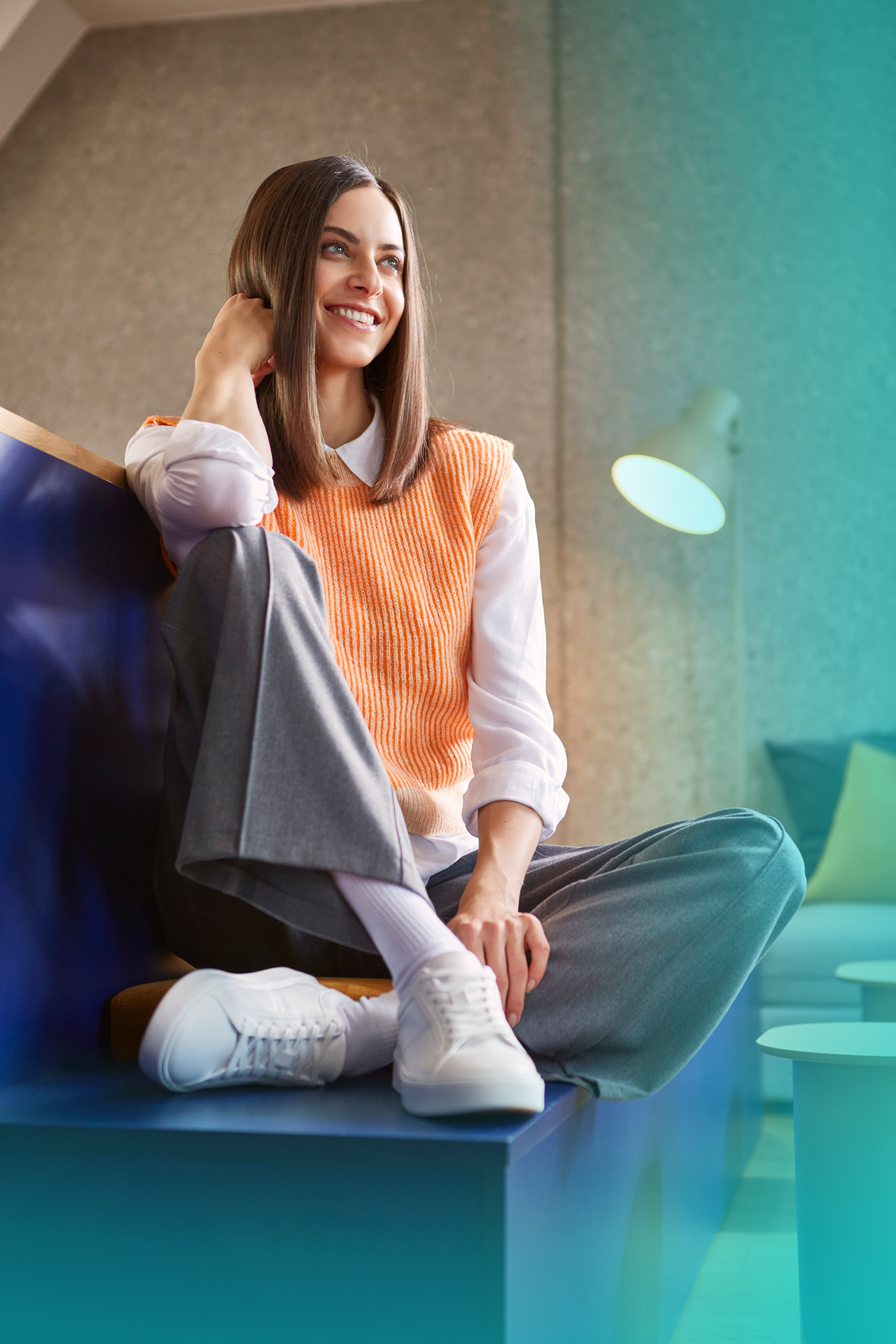 Frau sitzt im Gemeinschaftsraum mit orangem Pullover