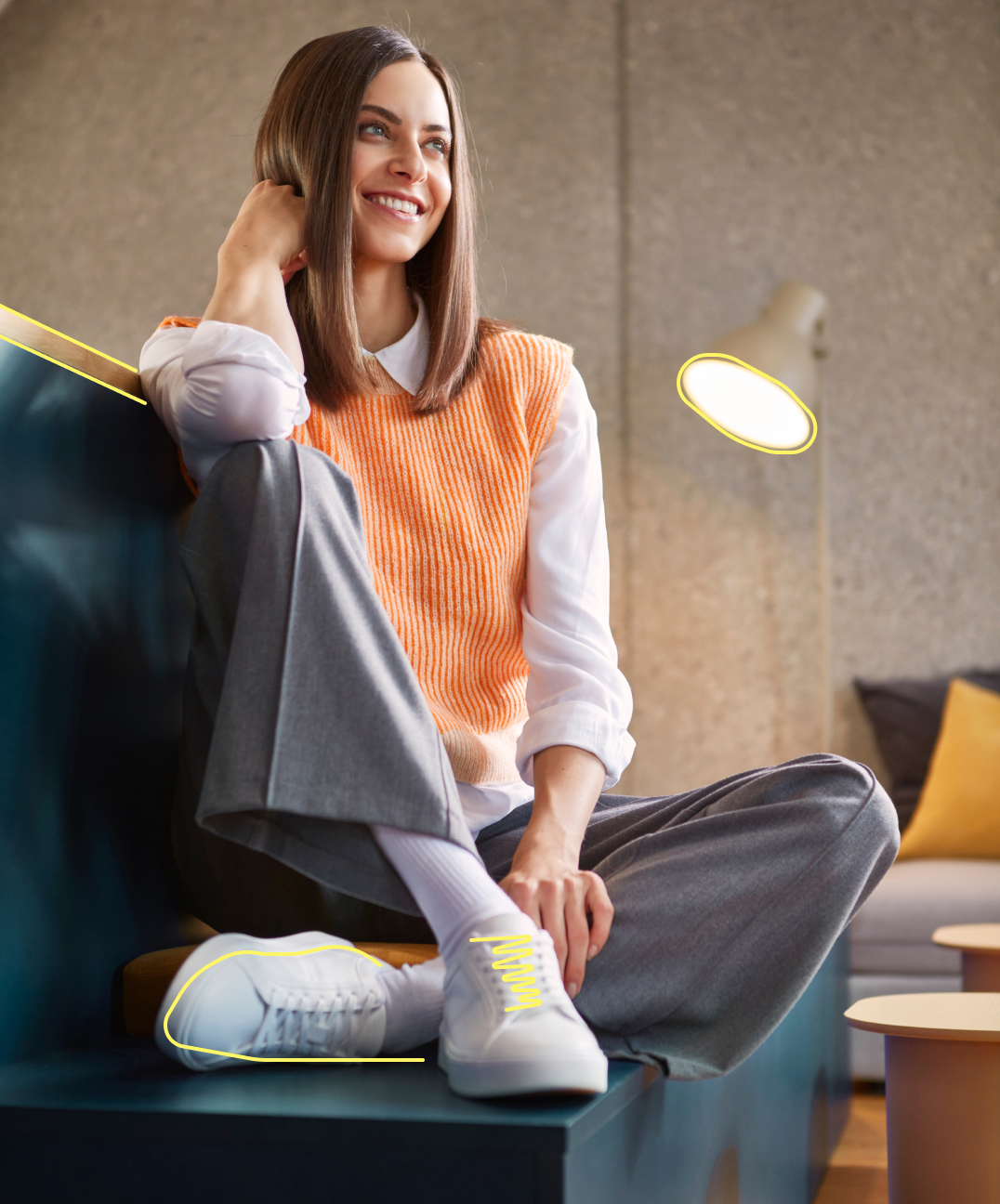 Frau sitzt im Gemeinschaftsraum mit orangem Pullover