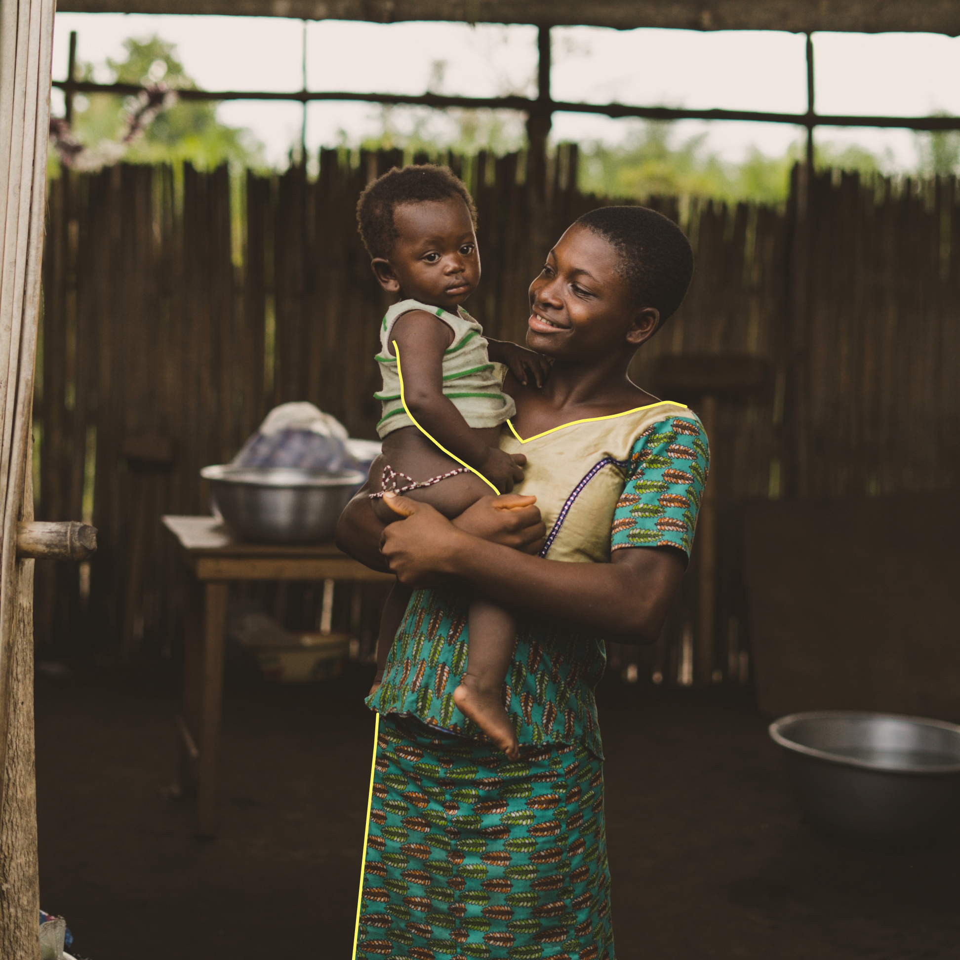 Eine afrikanische Mutter in traditioneller Kleidung hält ein Kind und lächelt