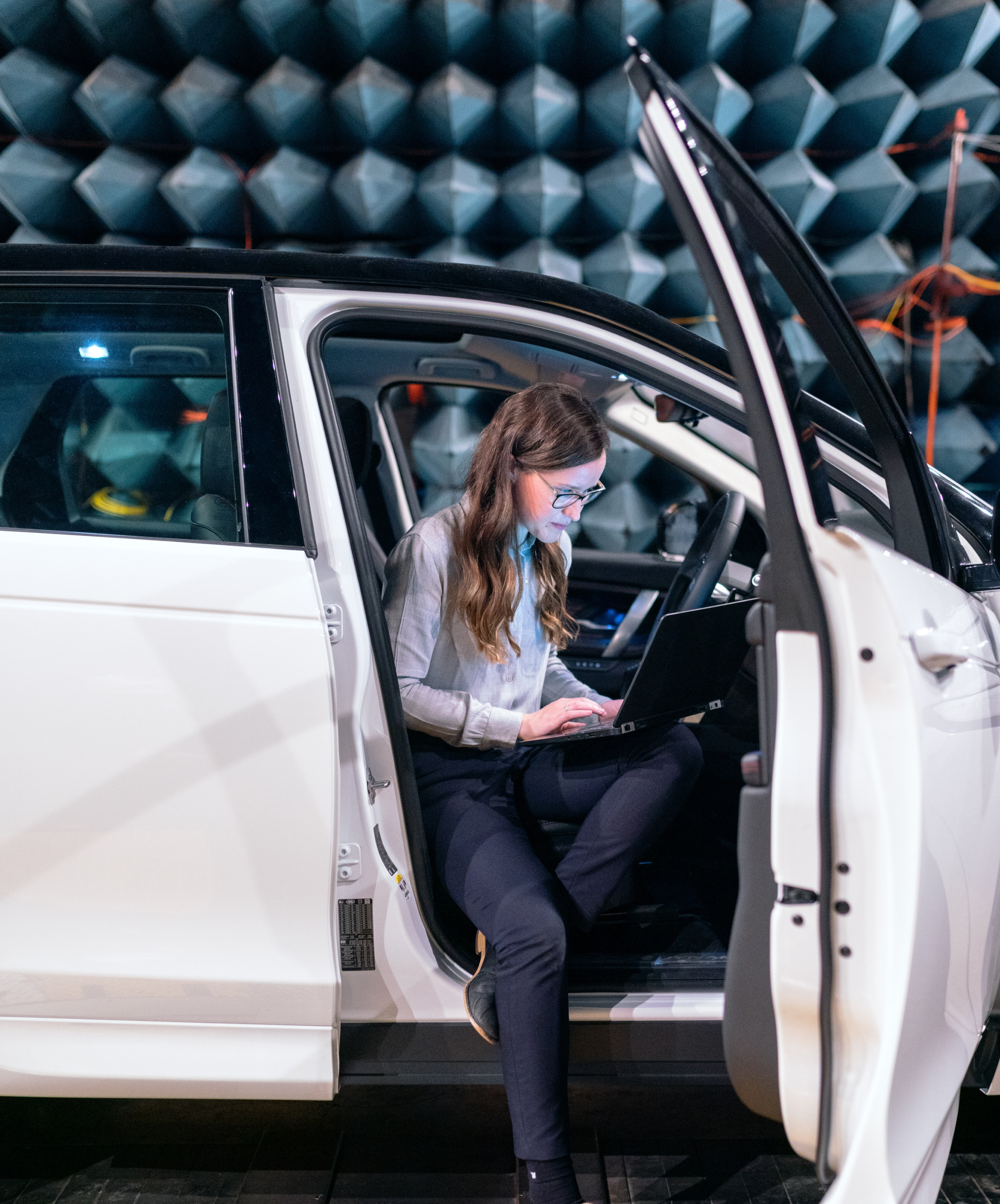Frau testet die Akustik eines Fahrzeugs mittels digitaler Messinstrumente