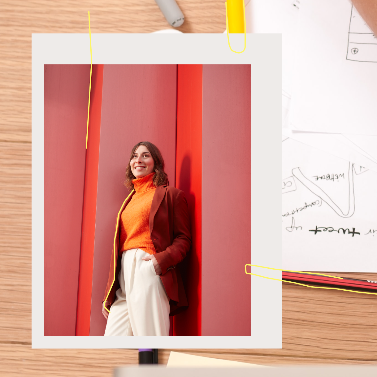 Frau vor roter Wand mit Schreibtisch im Hintergrund