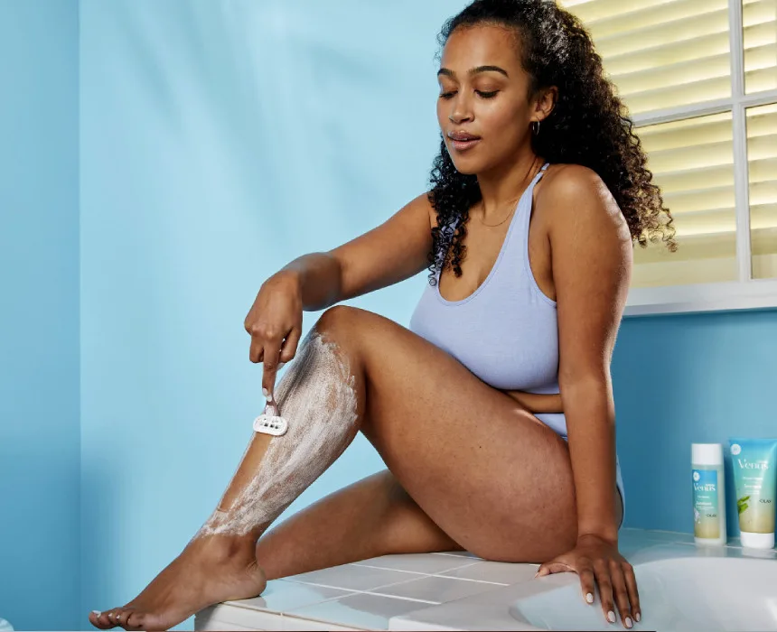 Frau rasiert sich im Badezimmer die Beine