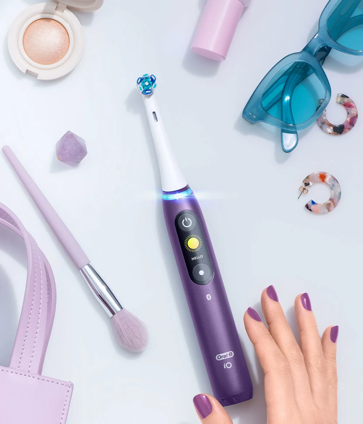 Flat lay con spazzolino elettrico Oral-B iO Series 8, occhiali da sole, borsetta e altri accessori 