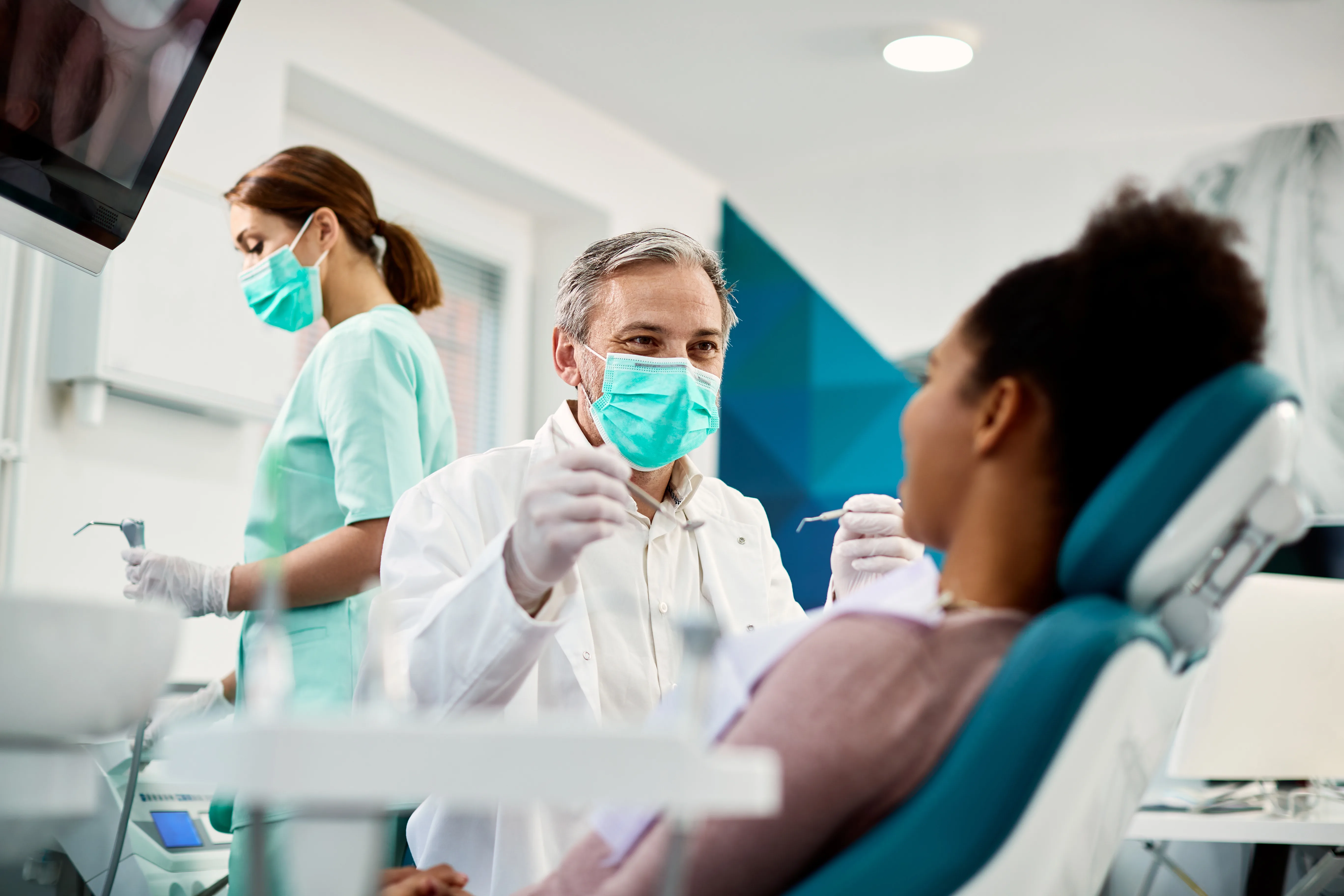 Vecchio dentista maschio che esamina una giovane paziente donna