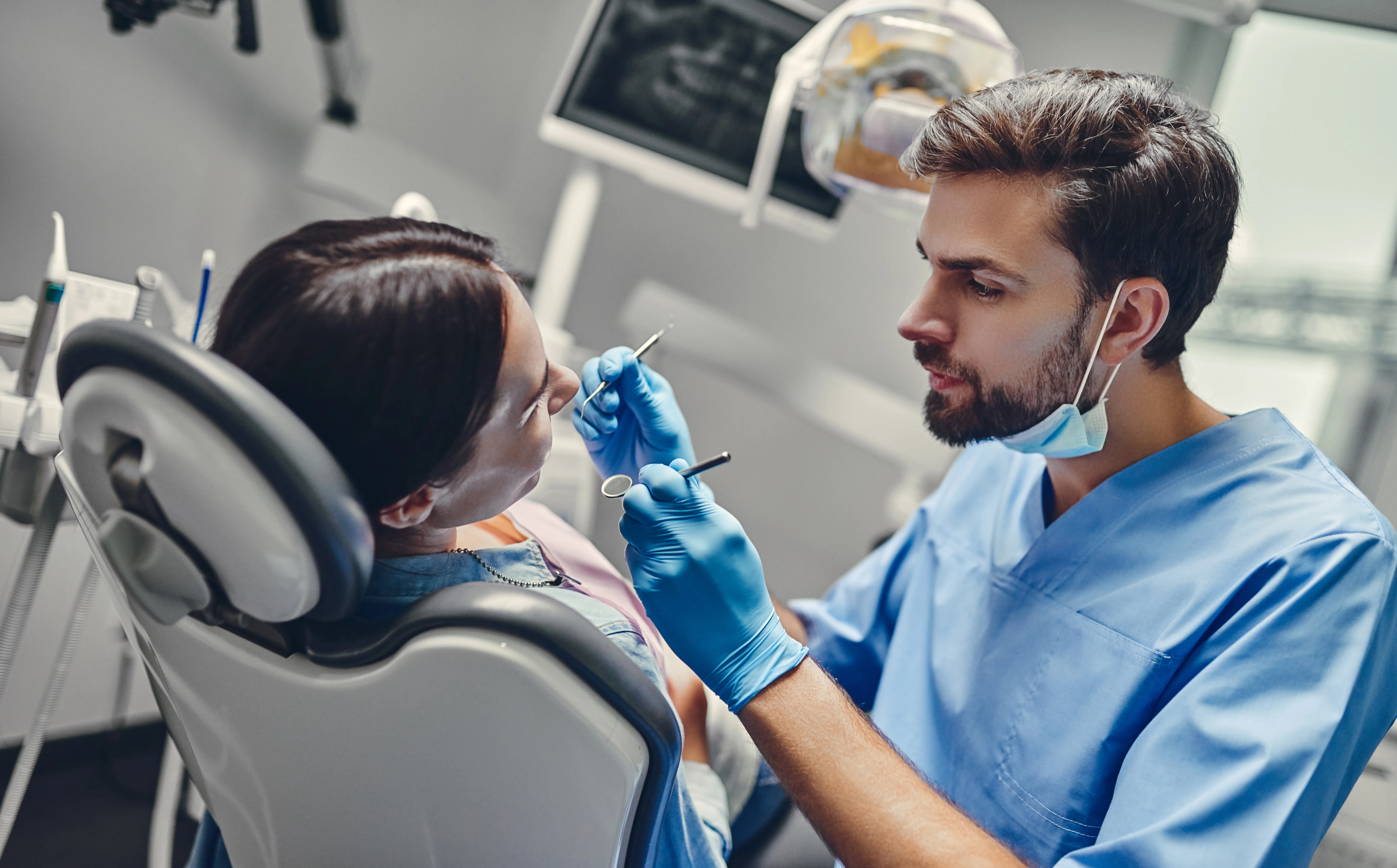 Dentista uomo che esamina una paziente donna.