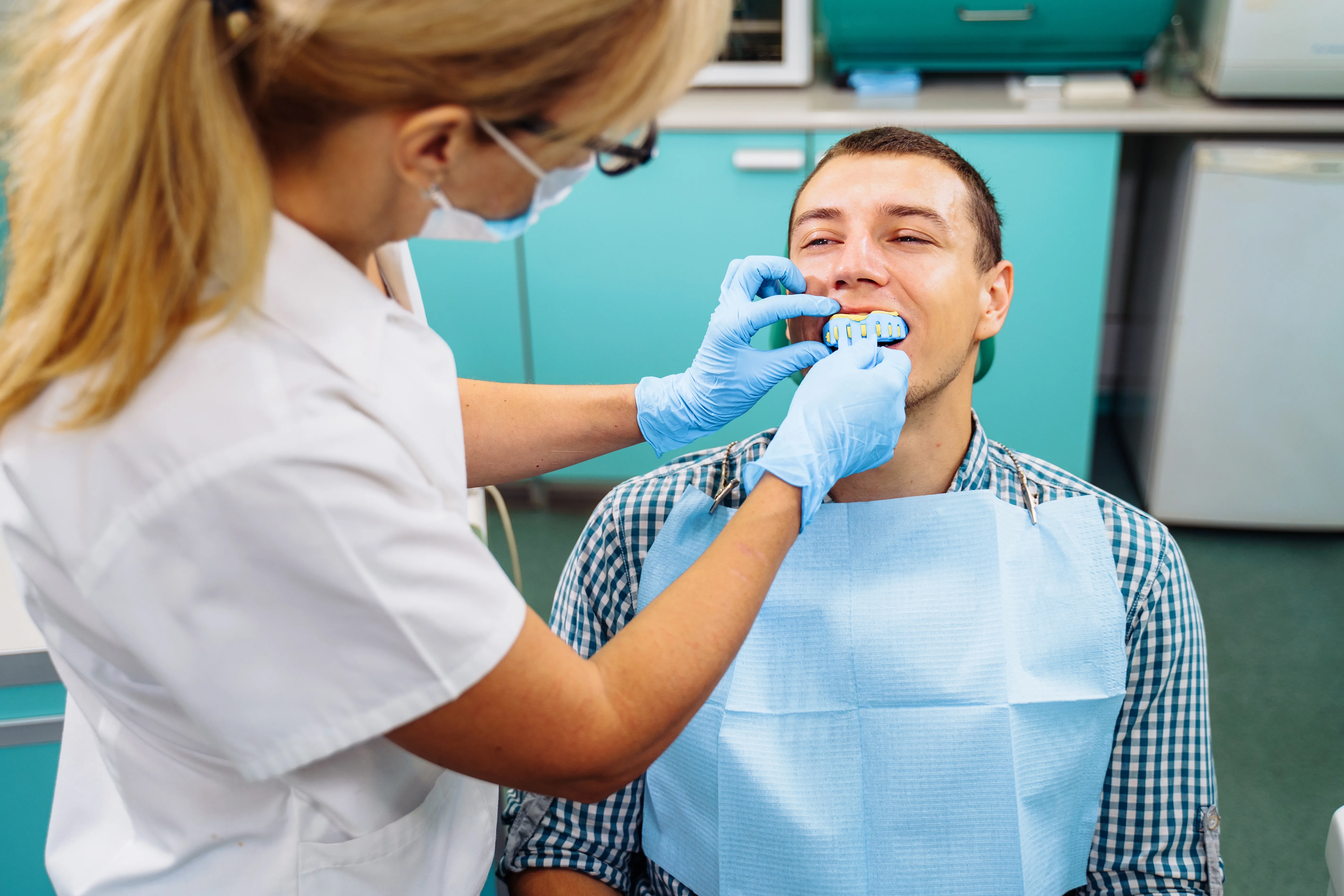 Dentista che esamina la bocca di un paziente in preparazione di una procedura di otturazione dentale.