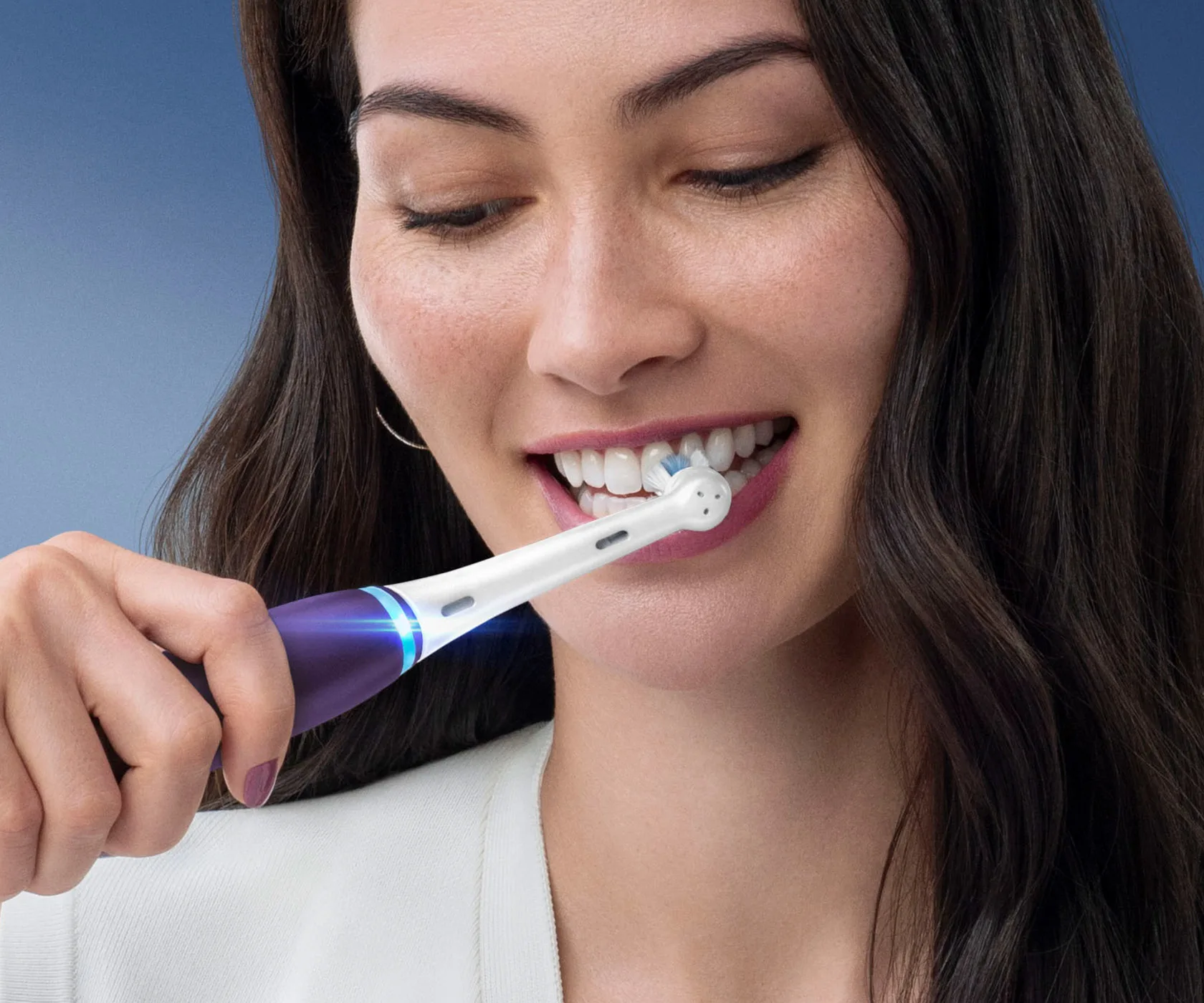Donna che si spazzola i denti con uno spazzolino elettrico viola Oral-B iO Series 8 