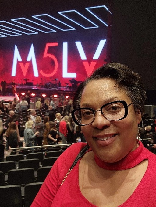 Closeup of HGV Member Cherise attending a concert at MGM Grand Las Vegas with lights and signage in the backgroun.