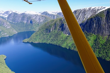 A plane in flight over a vista of land and water.  