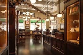 Interior of a book shop  with polished wood floors, vintage light fixtures and framed art lining the walls.
