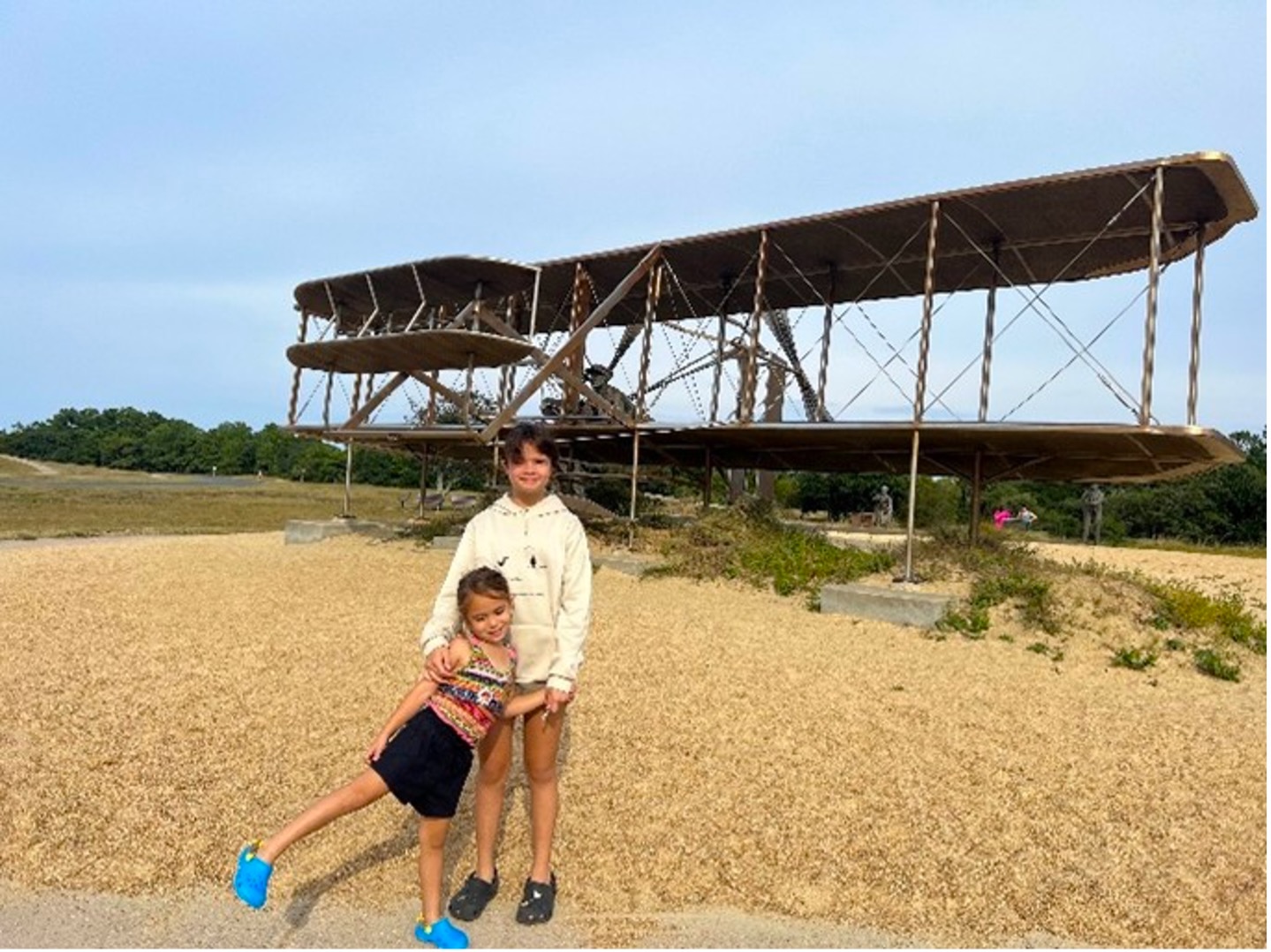 Two children standing in front of part of the Kitty Hawk memorial