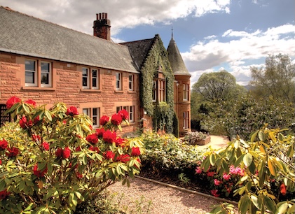 Scotland&rsquo;s Craigendarroch Suites with a chimney and an ivy-covered entryway surrounded by lush greenery, flowers and paths