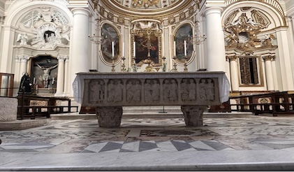 Picture of interior of the Church in Civita Castellana, featuring an altar in the foreground with frescos, ornate ceiling and walls in the background.
