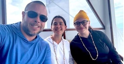 Three family members gathered closely, sitting and smiling.