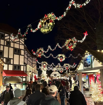 People strolling through festive streets with Christmas lights in Williamsburg.