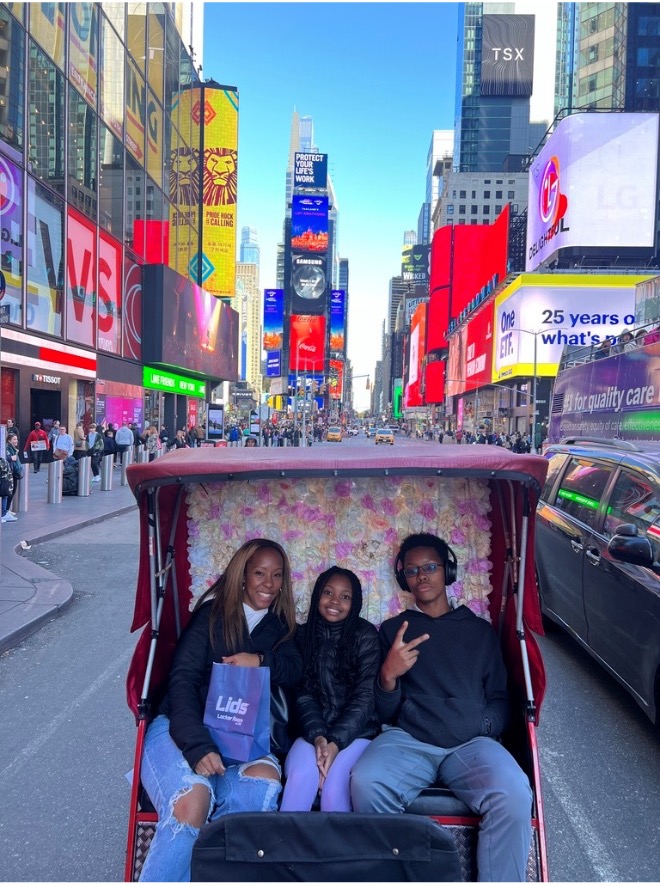 Mother, daughter and son enjoying a carriage ride in New York City with iconic buildings in the background