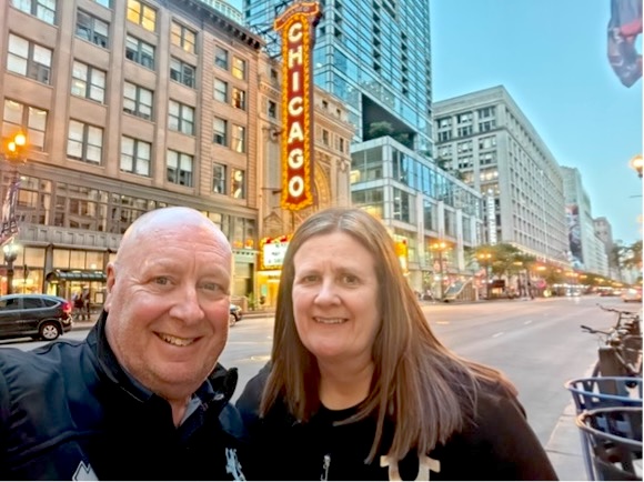 Smiling couple in Chicago in front of the iconic Chicago Theatre sign on State Street