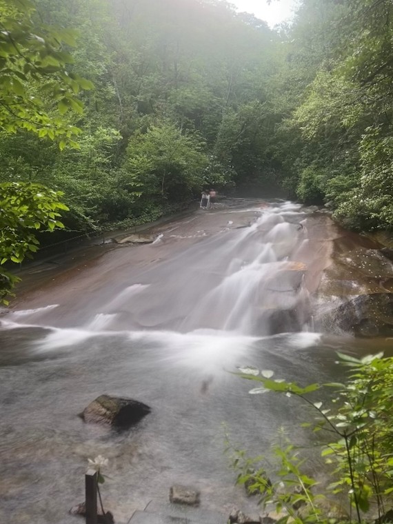 Sliding Rock waterfall rushing over rocks and surrounded by trees.