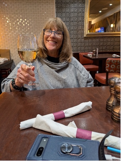 A picture of a woman raising a glass of wine in a restaurant.