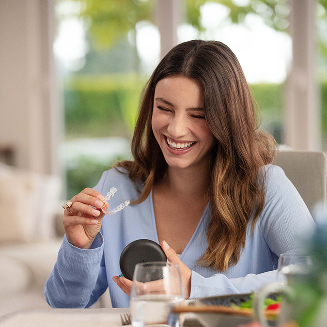 A smiling girl takes the Invisalign aligners out of their case