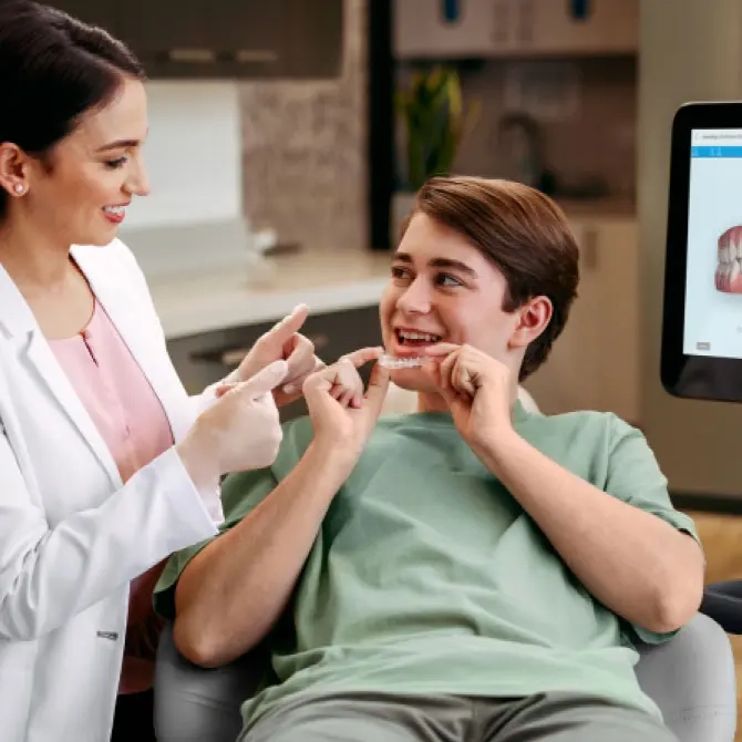 Female doctor showing her patient his Invisalign® aligners