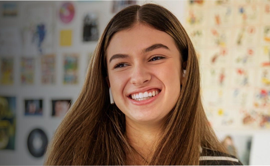 A teen girl is smiling with confidence after completing her Invisalign treatment.