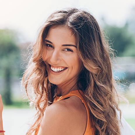 La ragazza con la maglietta arancione sorride dopo il trattamento Invisalign®