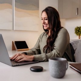 A brunette woman smiling and learning about Invisalign® on her computer