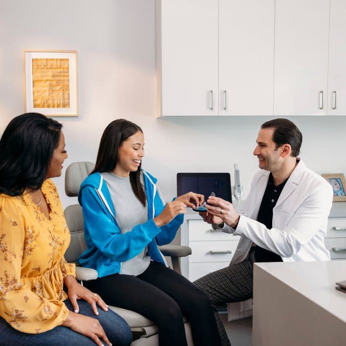 Kadın doktor, hastasına Invisalign® şeffaf plaklarını gösteriyor