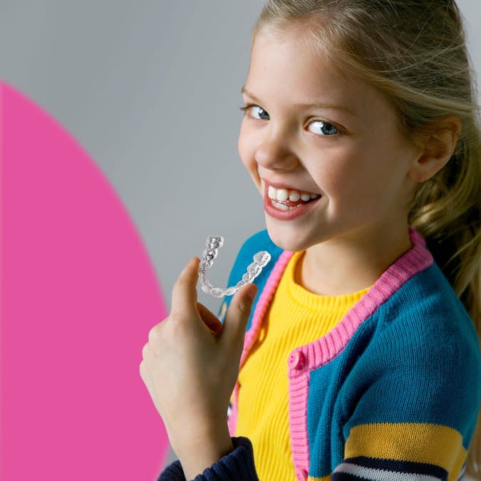 Little girl with Invisalign® clear aligners on blue and purple background
