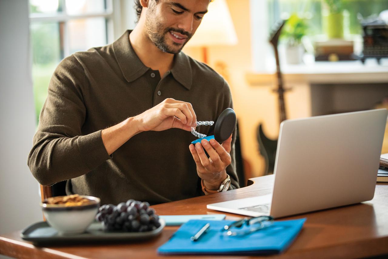 Man working at his office while holding aligners and case