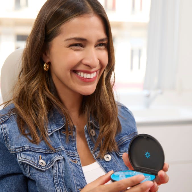 Mutlu bir kadın Invisalign® şeffaf plaklarını kutusunda gösteriyor