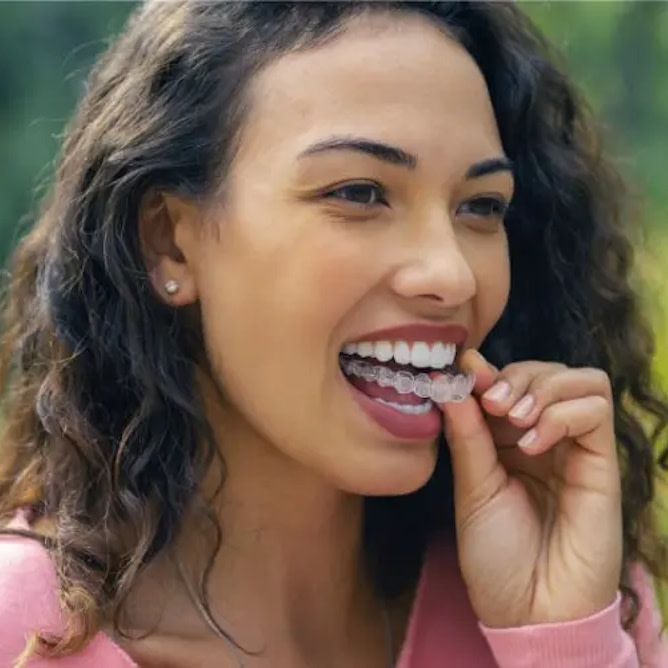 Woman putting on Invisalign® clear aligners