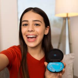 Genç bir kadın Invisalign şeffaf plak kutusunu tutuyor ve gülümsüyor