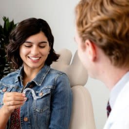 Kadın doktor, hastasına Invisalign® şeffaf plaklarını gösteriyor