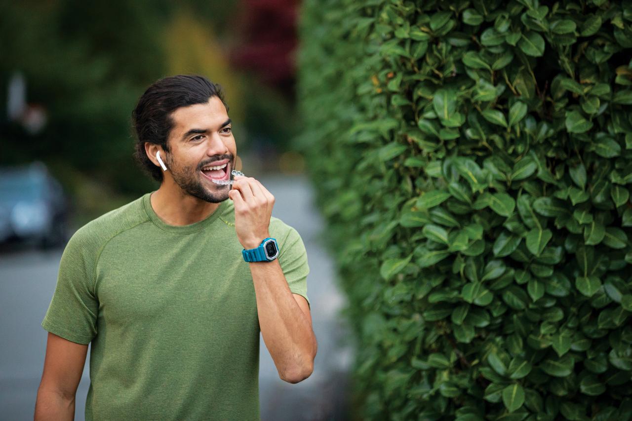 Young man in green shirt putting in his aligners