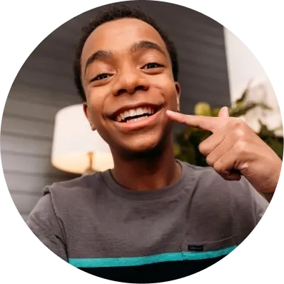 Teen boy pointing at Invisalign® clear aligners smiling