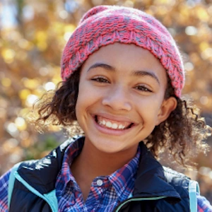 Little girl in pink hat smiling after Invisalign® treatment 