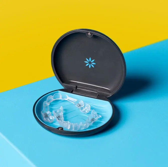 Allineatori Invisalign® nella loro custodia su sfondo giallo e blu