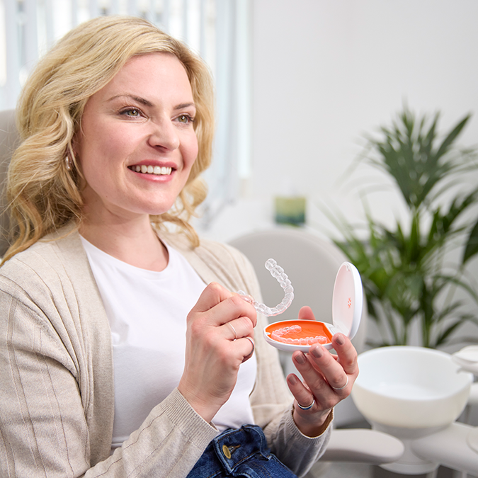 Blonde girl takes out her Invisalign aligners from their briefcase