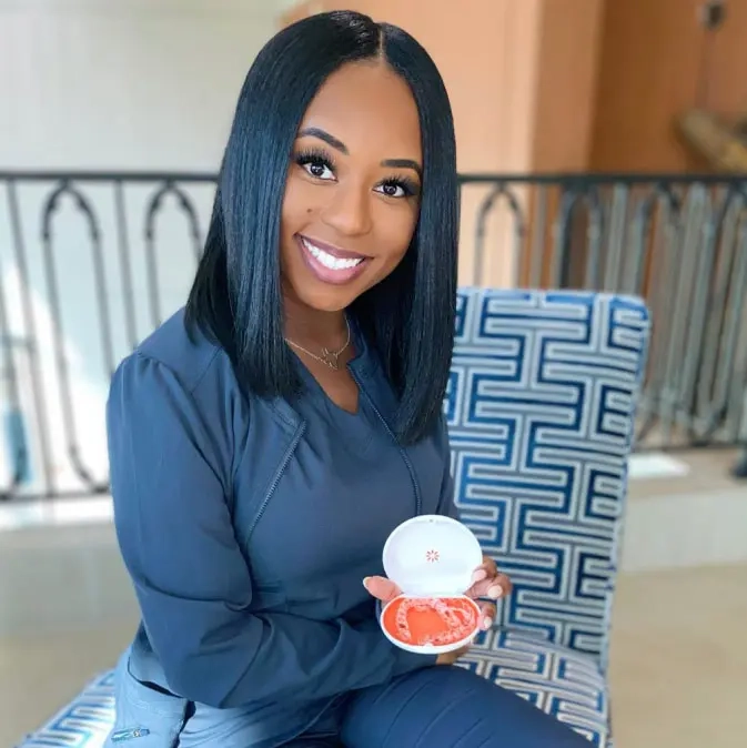 Ragazza seduta, sorridente, che tiene in mano la custodia aperta dei Vivera™ Retainers.