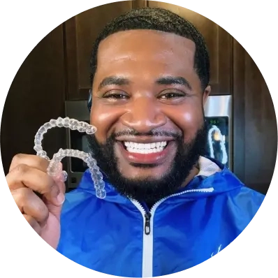 Mężczyzna trzyma swoje nakładki Invisalign® i uśmiecha się