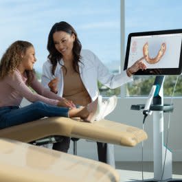 Doktor, çocuğa Invisalign® şeffaf plaklarını gösteriyor.