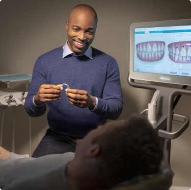 Invisalign® male doctor showing aligners to his male patient with iTero scanner