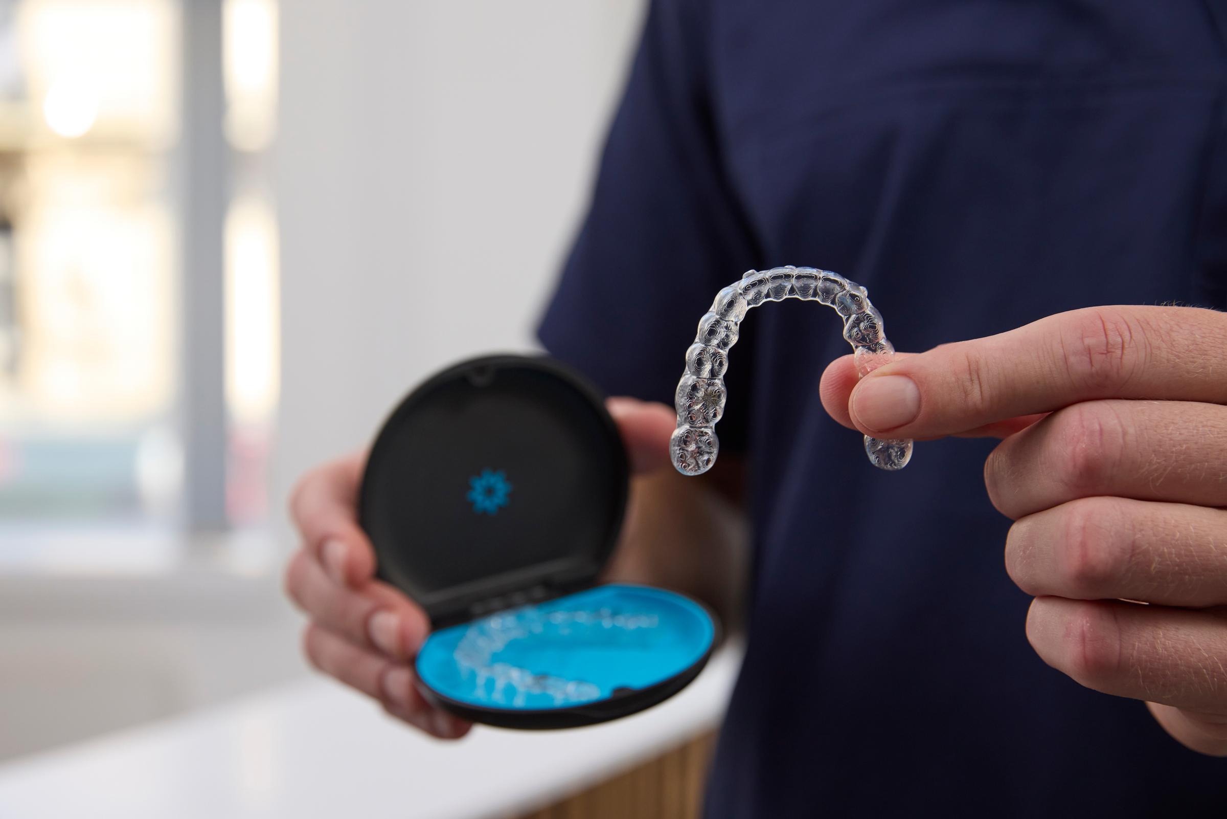 Hand holding Invisalign aligners and case