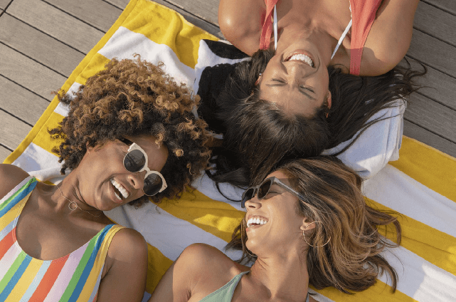 A group of smiling women enjoying a sunny day on a dock