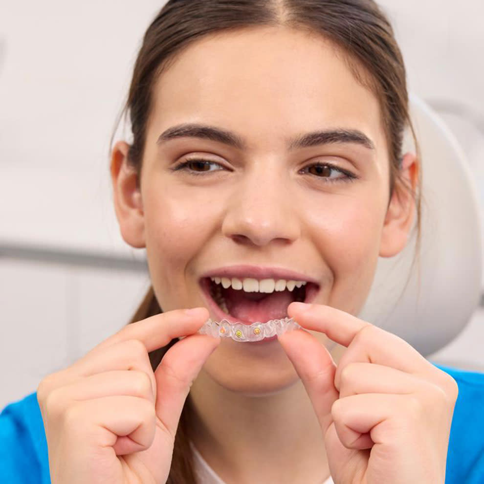 Ragazza con maglione blu che indossa gli aligner Invisalign®