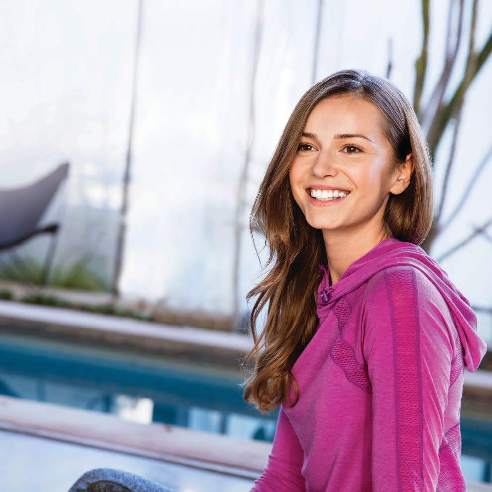 Bir genç kız elinde telefonu ile gülümsüyor